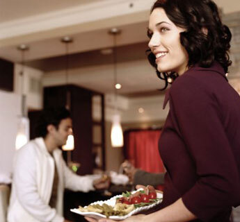 Woman holding food in an apartment with man in background